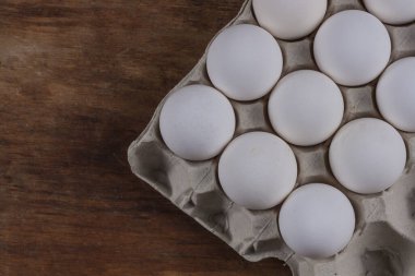 Tavuklu yumurtalar, ahşap bir masada gri bir Corton kutunun içinde.