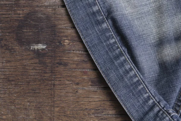 Blue denim jacket on a brown wooden table. View from above