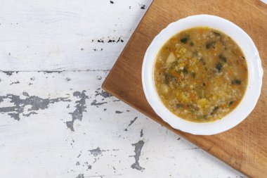 Beyaz yuvarlak bir tabakta pirinç çorbası. Gri bir demir masaya yakın plan. 