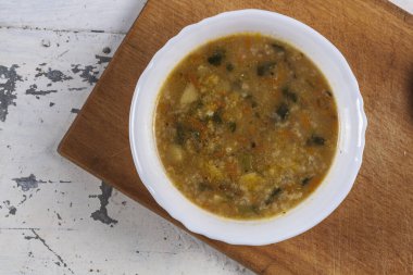 Beyaz yuvarlak bir tabakta pirinç çorbası. Gri bir demir masaya yakın plan. 