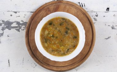 Beyaz yuvarlak bir tabakta pirinç çorbası. Gri bir demir masaya yakın plan. 