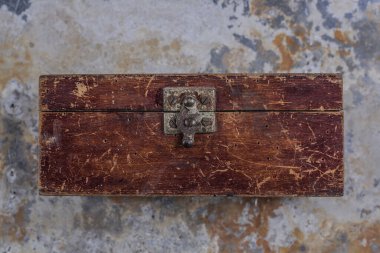 Old vintage wooden box with an iron lock on a gray iron table 