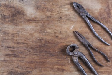 Kahverengi ahşap bir masada eski paslı inşaat aletleri. 