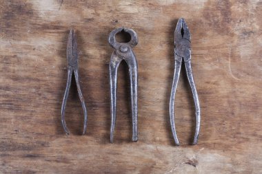 Kahverengi ahşap bir masada eski paslı inşaat aletleri. 