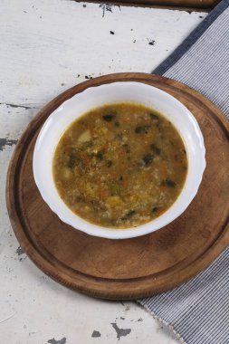 Beyaz yuvarlak bir tabakta pirinç çorbası. Gri bir demir masaya yakın plan. 