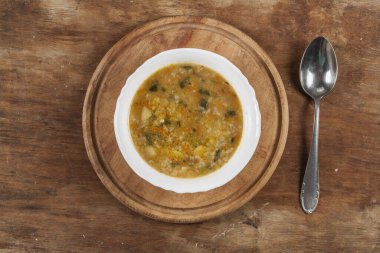 Beyaz yuvarlak tabakta pirinç çorbası Kahverengi ahşap bir masanın üstünde yakın plan