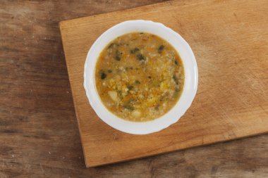 Beyaz yuvarlak tabakta pirinç çorbası Kahverengi ahşap bir masanın üstünde yakın plan