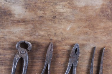 Kahverengi ahşap bir masada eski paslı inşaat aletleri. 