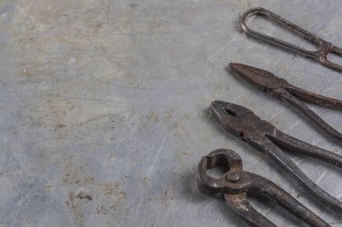 Gri bir demir zemin üzerinde eski paslı inşaat aletleri 
