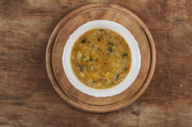 Beyaz yuvarlak tabakta pirinç çorbası Kahverengi ahşap bir masanın üstünde yakın plan