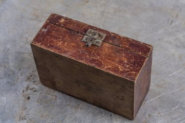 Old vintage wooden box with an iron lock on a gray iron table 