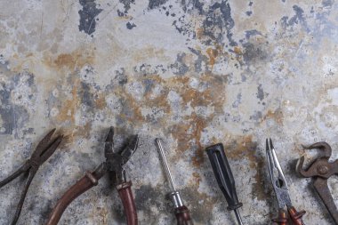 Gri bir demir zemin üzerinde eski paslı inşaat aletleri 