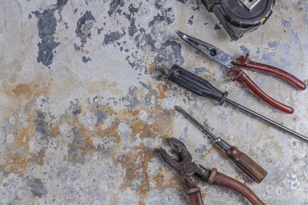 Gri bir demir zemin üzerinde eski paslı inşaat aletleri 