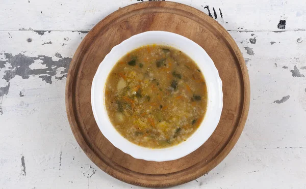 Beyaz yuvarlak bir tabakta pirinç çorbası. Gri bir demir masaya yakın plan. 