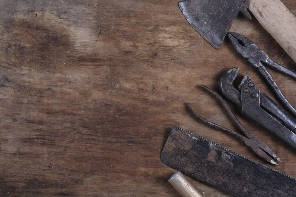 Kahverengi ahşap bir masada eski paslı inşaat aletleri. 