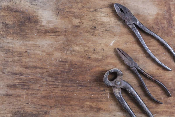 Kahverengi ahşap bir masada eski paslı inşaat aletleri. 