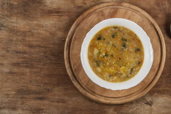 Beyaz yuvarlak tabakta pirinç çorbası Kahverengi ahşap bir masanın üstünde yakın plan