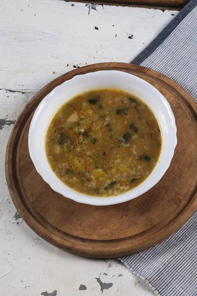 Beyaz yuvarlak bir tabakta pirinç çorbası. Gri bir demir masaya yakın plan. 