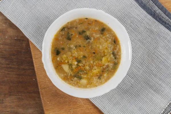 Beyaz yuvarlak tabakta pirinç çorbası Kahverengi ahşap bir masanın üstünde yakın plan