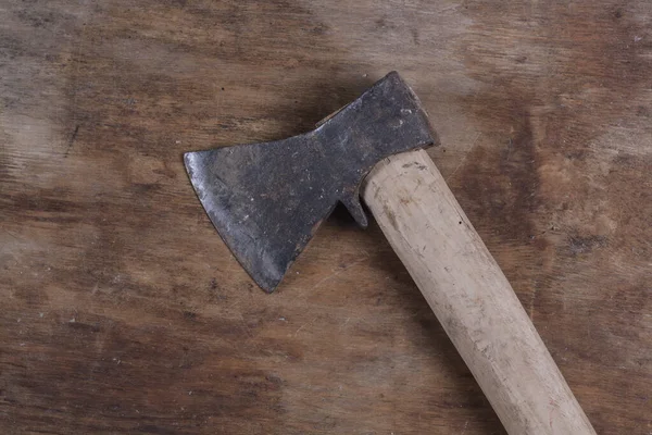 Eski balta, kahverengi tahta bir masada ağaç kesmek için bir araçtır.