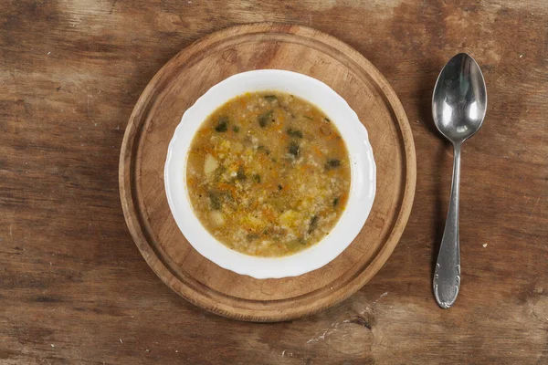 Beyaz yuvarlak tabakta pirinç çorbası Kahverengi ahşap bir masanın üstünde yakın plan