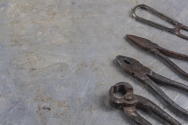 Gri bir demir zemin üzerinde eski paslı inşaat aletleri 