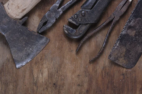 Old rusty construction tools on a brown wooden table 