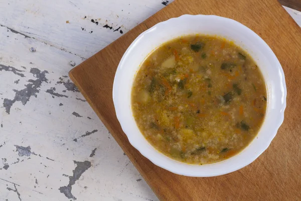 Beyaz yuvarlak bir tabakta pirinç çorbası. Gri bir demir masaya yakın plan. 