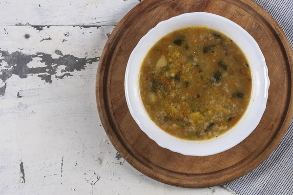 Beyaz yuvarlak bir tabakta pirinç çorbası. Gri bir demir masaya yakın plan. 