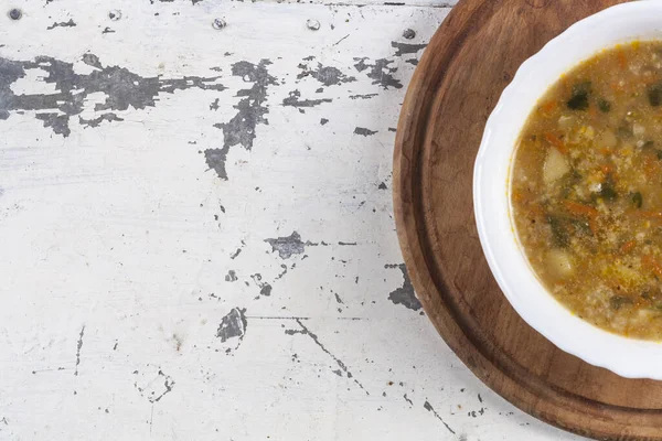 Beyaz yuvarlak bir tabakta pirinç çorbası. Gri bir demir masaya yakın plan. 