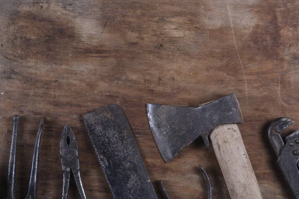 Kahverengi ahşap bir masada eski paslı inşaat aletleri. 