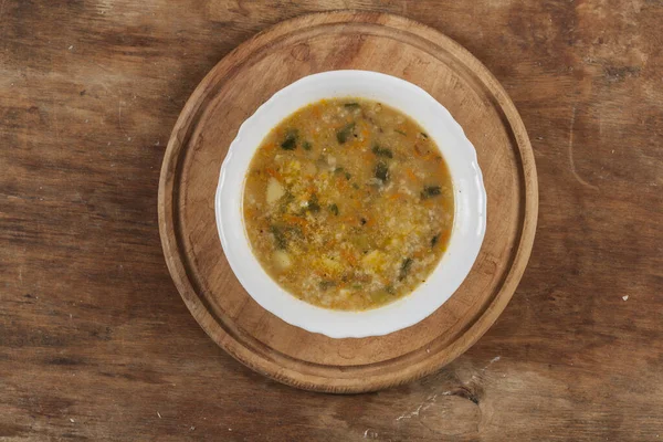 Beyaz yuvarlak tabakta pirinç çorbası Kahverengi ahşap bir masanın üstünde yakın plan