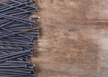 Ahşap arka planda gri renkli bir sürü çivi var.