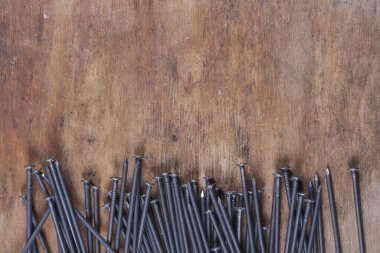 Ahşap arka planda gri renkli bir sürü çivi var.