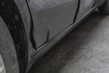 Siyah bir arabanın arka kapısı kırışmış.