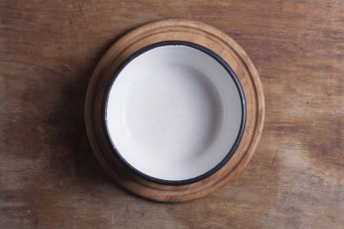 Ahşap mutfak masasında beyaz demir bir tabak.