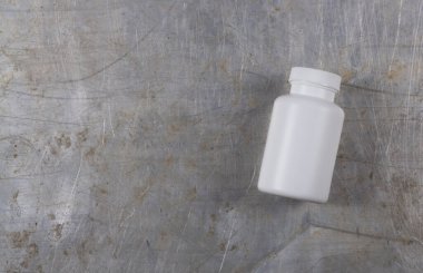 Beyaz plastik kavanoz ilaç ya da gri demir arka planda haplar için bir yazıt ya da logo için bir yer var.