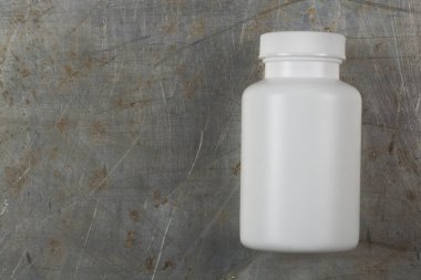 Beyaz plastik kavanoz ilaç ya da gri demir arka planda haplar için bir yazıt ya da logo için bir yer var.
