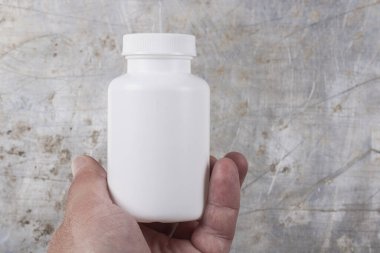 Beyaz plastik kavanoz ilaç ya da gri demir arka planda haplar için bir yazıt ya da logo için bir yer var.
