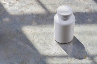 White plastic jar for medicines or pills on a gray iron background, there is a place for an inscription or your logo