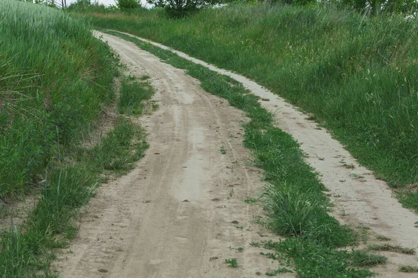 Dirt road in the countryside, road trail through the fields on a sunny day.