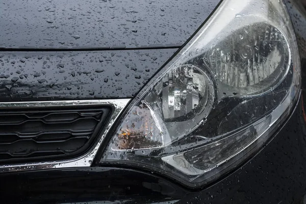 Headlight of a car in rainy time with drops close-up