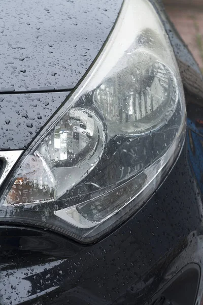 Headlight of a car in rainy time with drops close-up