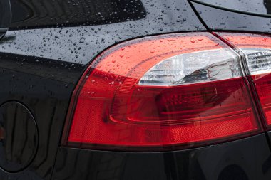 Yağmurlu bir zamanda damlaları yakın plan çekilmiş bir arabanın farları.