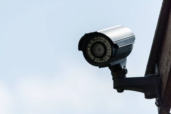 Close-up of a small surveillance camera on the roof of a house. Surveillance and protection of the yard and home