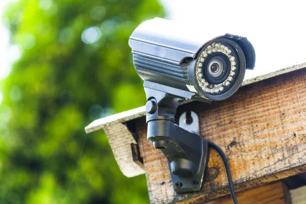 Close-up of a small surveillance camera on the roof of a house. Surveillance and protection of the yard and home