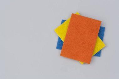 Multicolored sponge for washing dishes on a solid gray background, close-up