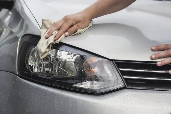 The process of rubbing the hood on a passenger car. Silver car wash