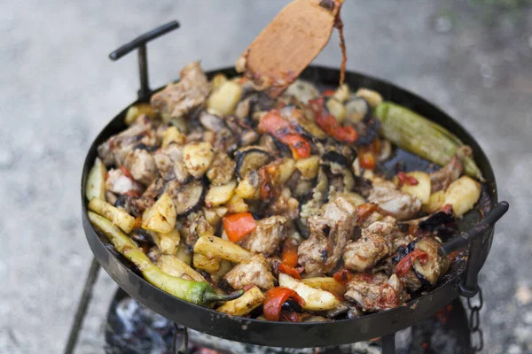 Cooking caucasian food on the fire on the grill, meat dish with vegetables on the fire