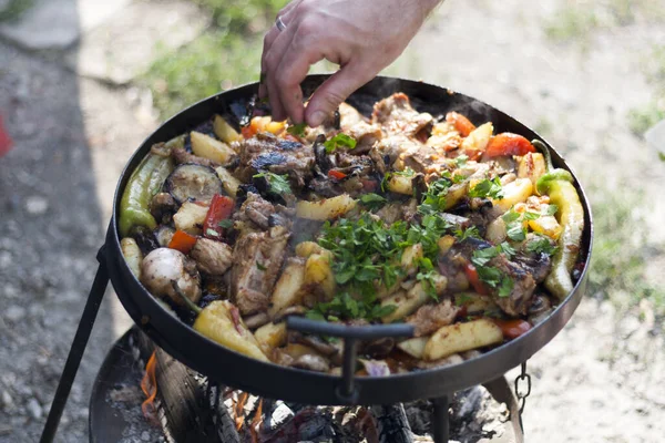 Cooking caucasian food on the fire on the grill, meat dish with vegetables on the fire